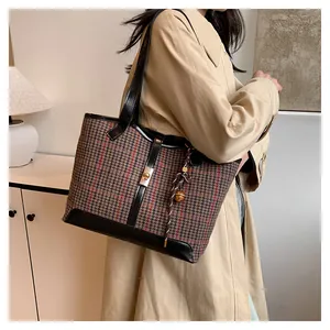 Detail of checkered woolen tote bag with leather trim and gold hardware accents