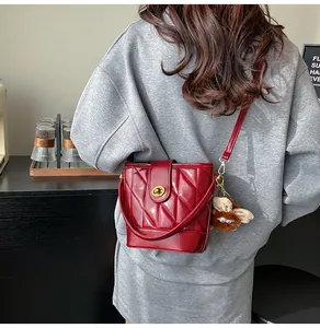 Détail du sac seau rouge matelassé avec fermoir rotatif métallique et breloque en peluche