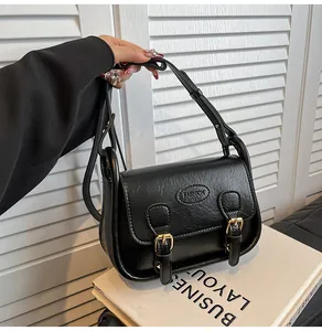 Close-up of black PU leather saddle bag with gold metal buckle straps and FASHION logo