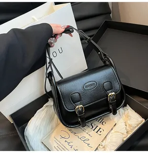 Detail of black vintage PU saddle bag with gold fashion plaque and buckle straps
