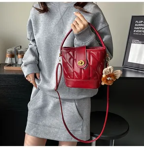 Détail d'un sac seau matelassé bordeaux avec fermoir doré et pendentif en peluche doux