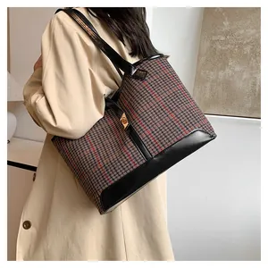Close-up of houndstooth wool tote bag with black leather trim and gold metal swivel lock
