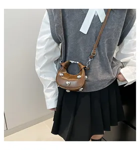 Brown leather half-moon bag featuring silver studs and adjustable shoulder strap