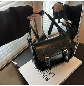 Close-up of black PU leather saddle bag featuring gold buckles and FASHION embossed logo