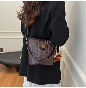 Gros plan d'un sac seau marron foncé à carreaux avec fermoir doré et charme en peluche