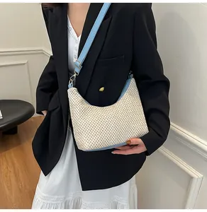 Détail du sac tressé avec bandoulière en cuir bleu et boucle dorée réglable pour femme