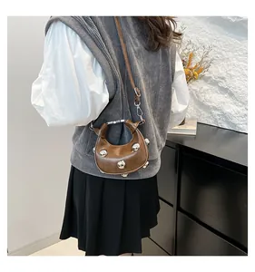 Detail of brown leather moon bag with silver sphere studs and a knotted handle strap