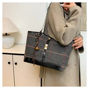 Detail shot of grey woolen tote bag featuring a gold twist lock and a decorative pendant