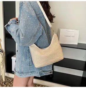 Détail du sac demi-lune en paille tressée avec bandoulière en cuir blanc et boucle métal