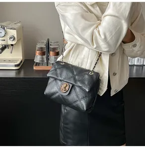 Detail einer schwarzen Stepptasche mit goldenem Löwenemblem an der Verschlussklappe