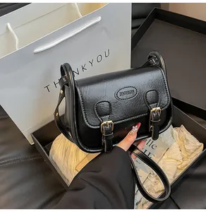 Detail of black vintage PU leather saddle bag with fashion embossing and metal buckle