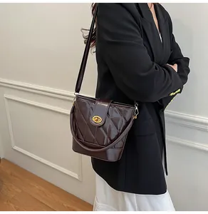 Détail du sac seau bordeaux en cuir verni matelassé avec fermoir tournant doré et sangle