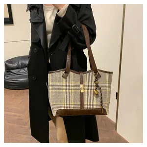 Houndstooth pattern tote bag with leather trim and gold buckle shown on a model