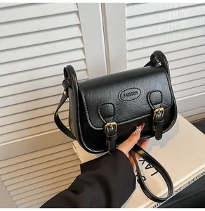 Detail of black vintage PU leather saddle bag with gold buckles and fashion logo