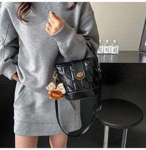 Détail du sac seau noir matelassé avec fermoir doré et pendentif peluche marron