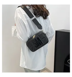 Achteraanzicht model met zwarte crossbodytas met SM-reliëf en brede schouderband
