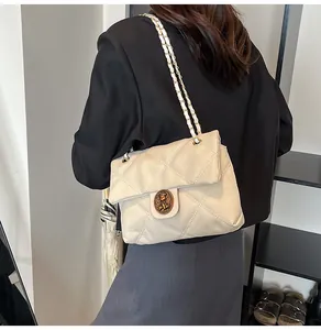 Nahaufnahme der beigen Stepptasche mit goldener Schnalle und geflochtener Lederkette