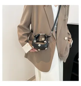 Detailed view of black half-moon crossbody bag featuring silver spherical studs on smooth leather