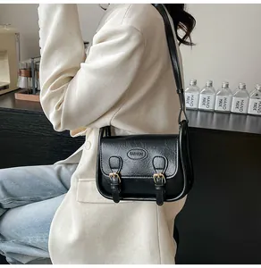 Close-up of black retro saddle bag with gold metal buckles and fashion lettering decoration