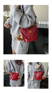 Vues détaillées du sac seau rouge matelassé avec fermoir doré et accessoire ours en peluche