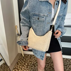 Sac demi-lune chic en paille crème avec bandoulière en cuir porté par un mannequin en style