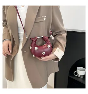 Detail of burgundy crescent mini bag with silver sphere accents and knotted top handle