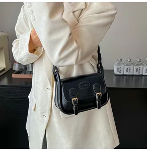 Detail of black vintage PU leather saddle bag with double buckles and fashion embossing