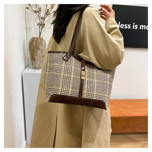 Detail of wool plaid tote bag with dark brown leather straps and gold metal buckle
