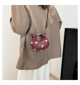 Detail of burgundy leather crescent bag with silver metallic sphere decorations and strap