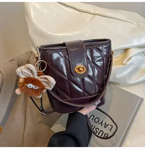 Gros plan du sac seau matelassé violet avec fermoir doré et breloque en peluche