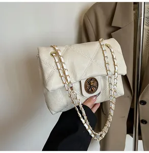 Nahaufnahme der cremefarbenen Stepptasche mit Vintage-Goldemblem und Kettenriemen