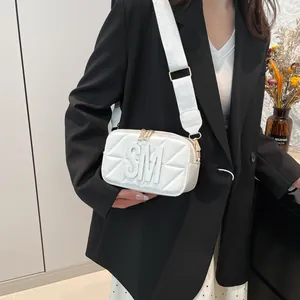 Witte gewatteerde crossbodytas met SM-logo en brede stoffen riem gedragen door model