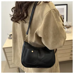 Detail of black leather hobo bag with gold buckle and decorative pocket on the side