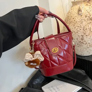 Sac seau matelassé bordeaux avec fermoir doré et pendentif en peluche chic et mode