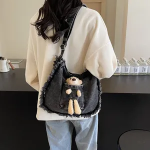 Detail view of a vintage dark grey denim tote bag featuring a cute plush bear decoration