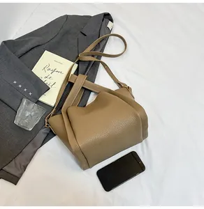 Top view of a structured khaki lychee pattern leather bucket bag with lifestyle accessories