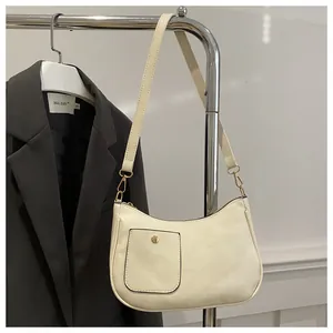 Detail der cremeweißen Schultertasche aus Kunstleder mit Goldschnalle und Tasche