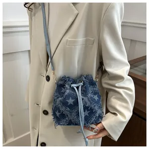 Detail of denim bucket bag with star print and frayed edges on a beige blazer