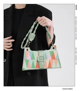 Détail de la bandoulière en cuir tressé et de la boucle verte sur le sac coloré