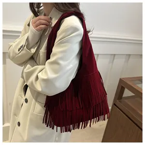 Macro shot of burgundy suede shoulder bag with triple-layered fringe tassels detail