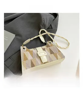 Détail du sac à motif géométrique avec bandoulière en cuir tressé sur un blazer gris