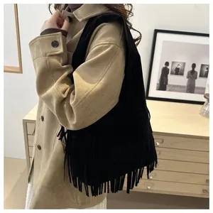Detail of black faux suede tote bag featuring long fringes and bohemian vintage style