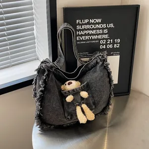 Detailed view of grey denim tote bag with frayed edges and cute plush bear in pocket