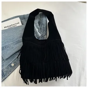 Detail of black faux suede fringe bag with dense tassels and wide shoulder strap texture