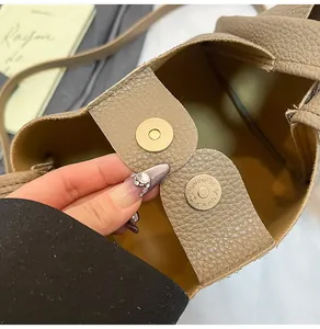 Detail of lychee pattern leather bucket bag with double matte gold magnetic buckles
