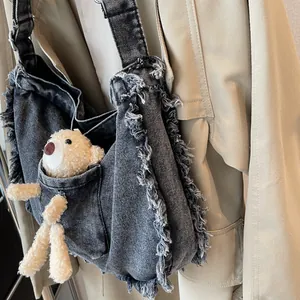 Detail of black denim tote bag with frayed edges and cute small plush bear accessory