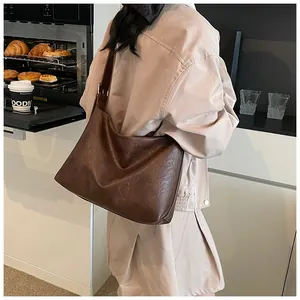 Bolso de hombro grande marrón oscuro en piel sintética usado por modelo en escena