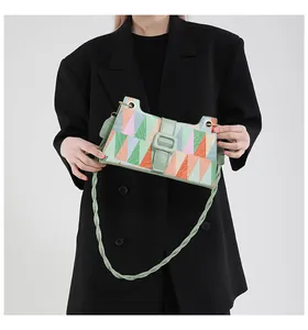 Détail du sac bandoulière à motif géométrique multicolore et bandoulière verte tressée