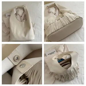 Detail of cream leather tote showing long fringe accents and magnetic closure with interior space