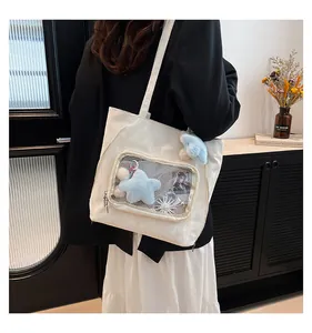 White canvas ita bag featuring a large clear PVC window and cute blue mushroom plush charm